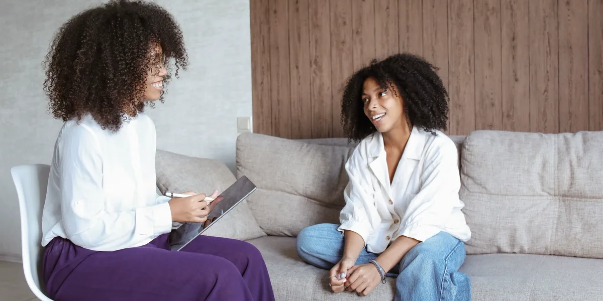 Two women talking calmly on a sofa during a counselling conversation